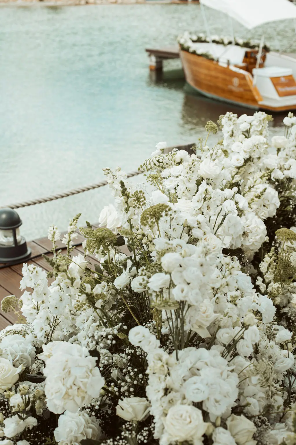 Witte bloemen aan de steiger, met de sloep op de achtergrond