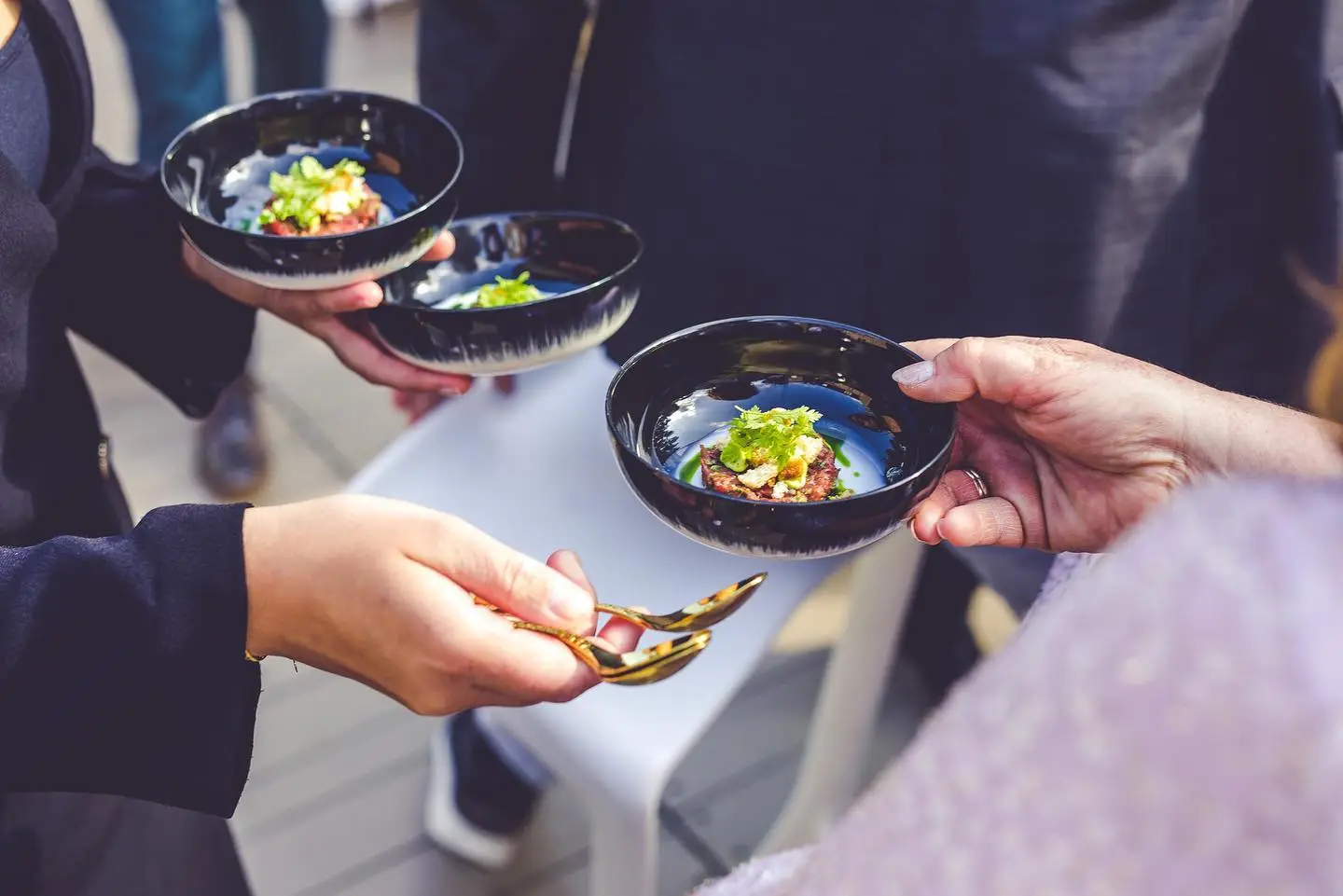 Gasten krijgen amuses in donkere schaaltjes aangereikt tijdens een zakelijk event